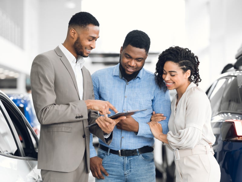 Dealer showing car options to a couple